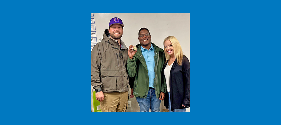 Three ACRT team members stand together smiling, with Alex Fields holding his ACRT Safety Challenge Coin.